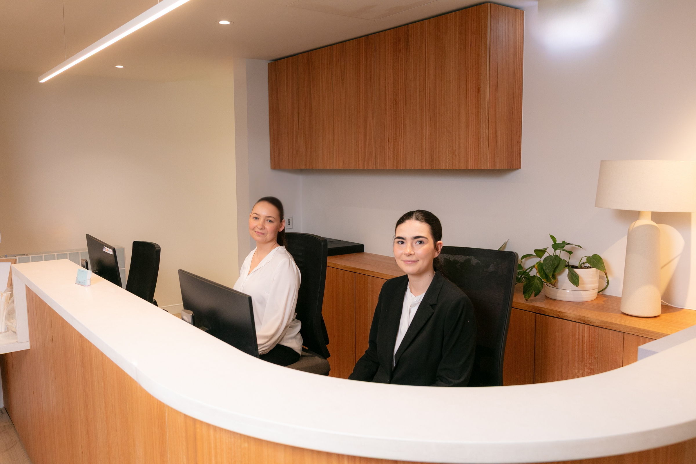 Two women at a reception desk in an office setting
