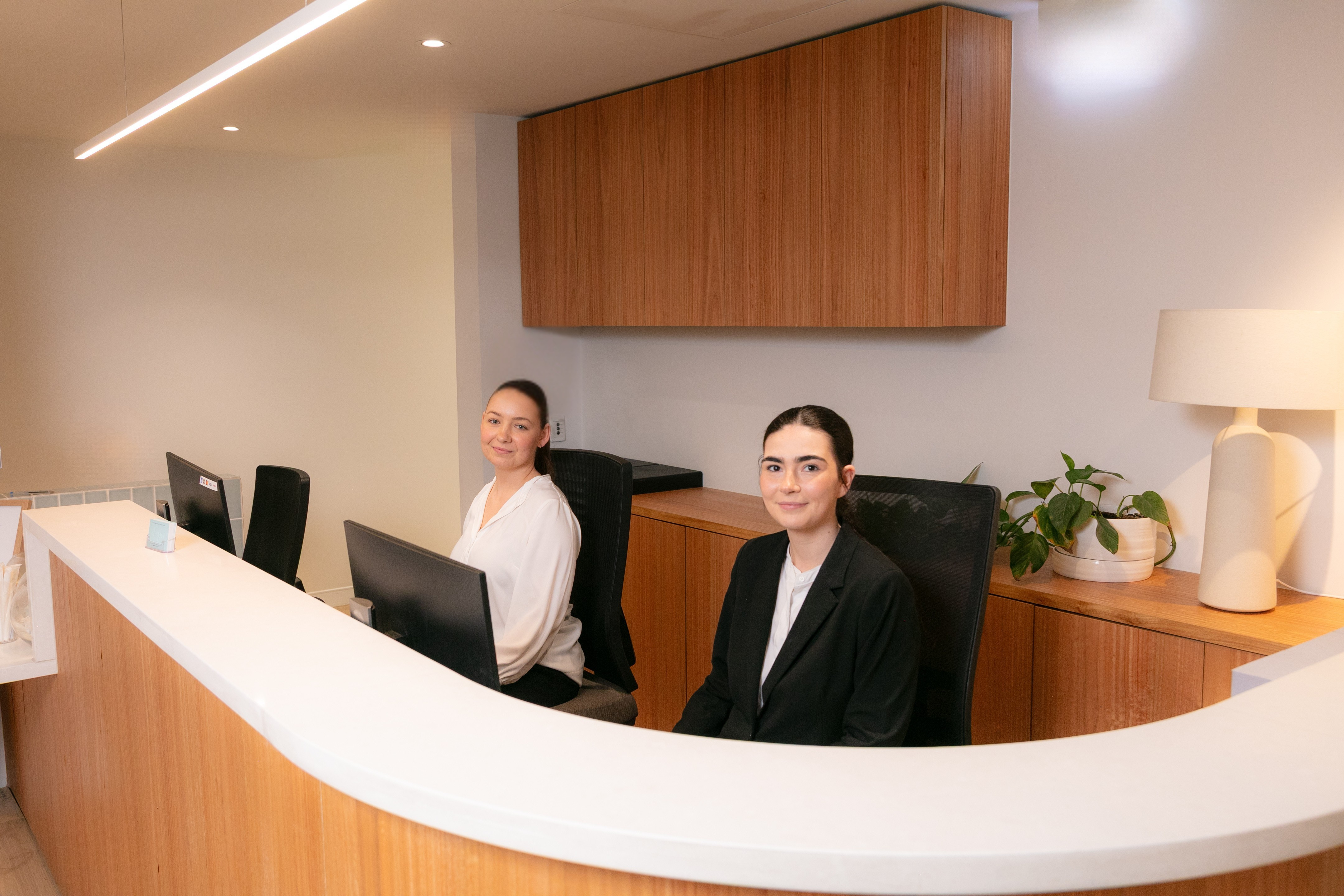 Two women at a reception desk in an office setting